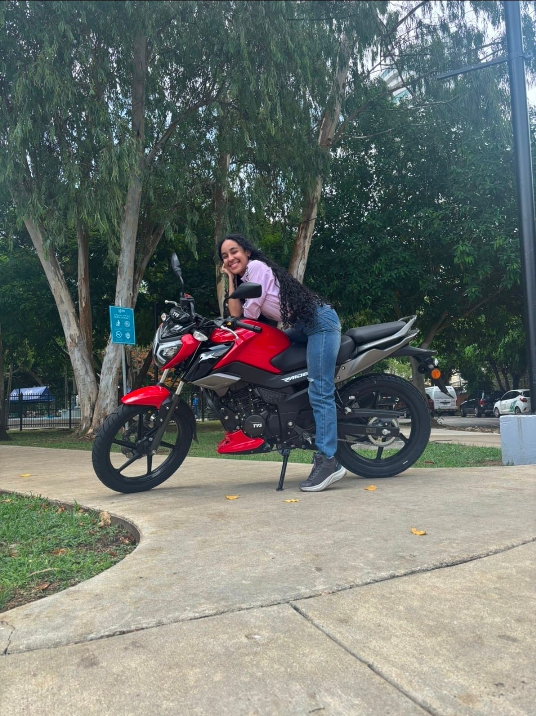 Yinelis sonriendo junto a una motocicleta roja