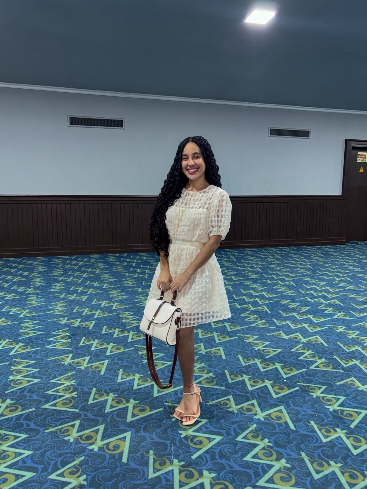 Yinelis sonriendo con sus rulos y un vestido blanco